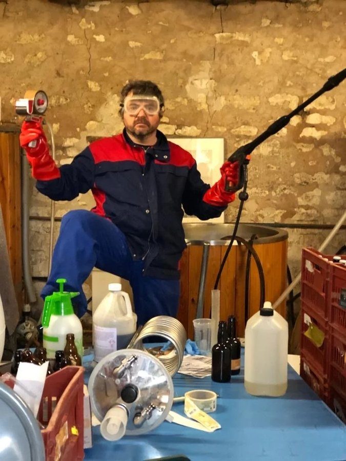 Tommy Barnes in the original Braslou brewhouse, in overalls and safety goggles, holding a pressure washer